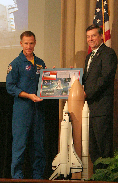 Chris Ferguson presents SSC Director Patrick Scheuermann with mission photos and a flag that was brought into orbit on STS-135.